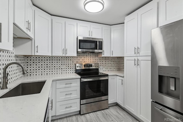 695 S Alton Way Unit 5A, Denver, CO 80247 - kitchen with appliances with stainless steel finishes, white cabinetry, backsplash, light wood-style flooring, and light stone countertops