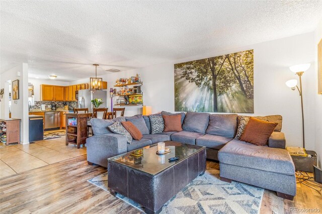 2279 Coronado Pkwy Unit B, Denver, CO 80229 - living room featuring light wood-type flooring, a notable chandelier, and a textured ceiling