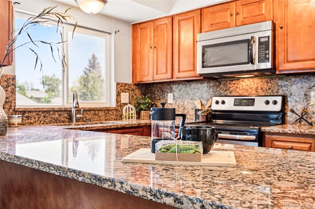 5202 Dillon St, Denver, CO 80239 - kitchen featuring stainless steel appliances, decorative backsplash, light stone counters, and a sink