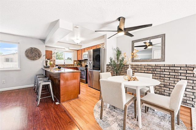5202 Dillon St, Denver, CO 80239 - dining space with light wood finished floors, a textured ceiling, a ceiling fan, and baseboards