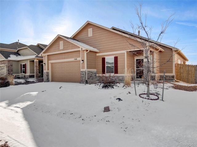 view of front of property featuring a garage, stone siding, and fence