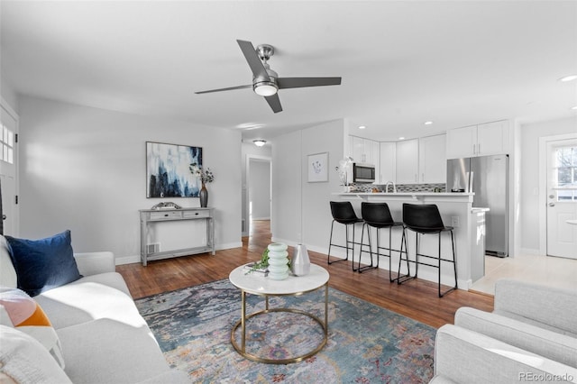 living room with sink, ceiling fan, and light hardwood / wood-style floors