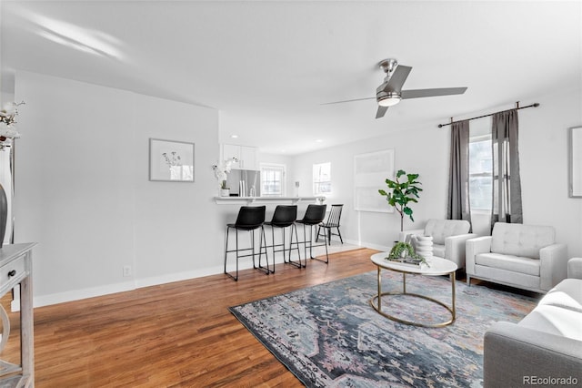 living room featuring wood-type flooring, ceiling fan, and plenty of natural light