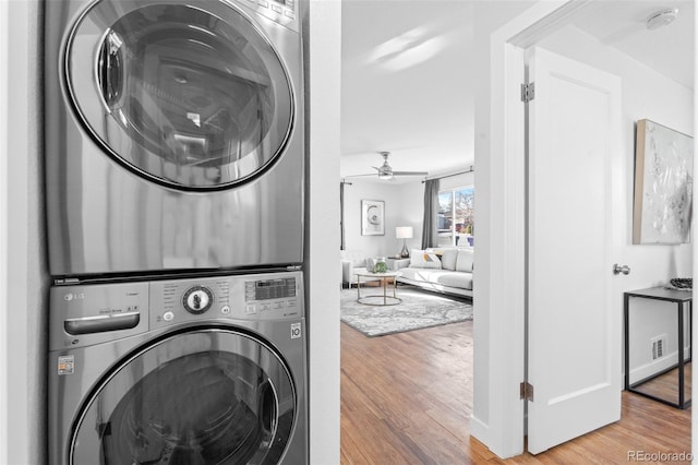 clothes washing area featuring stacked washer / drying machine, light wood-type flooring, and ceiling fan