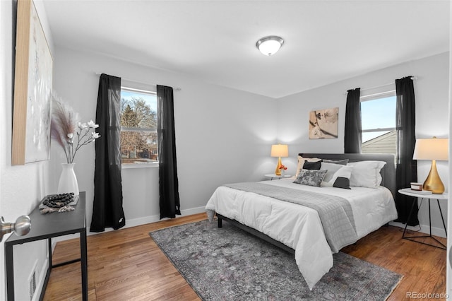 bedroom with hardwood / wood-style flooring and multiple windows