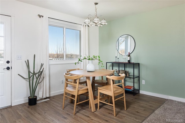 dining space with dark hardwood / wood-style flooring and a chandelier