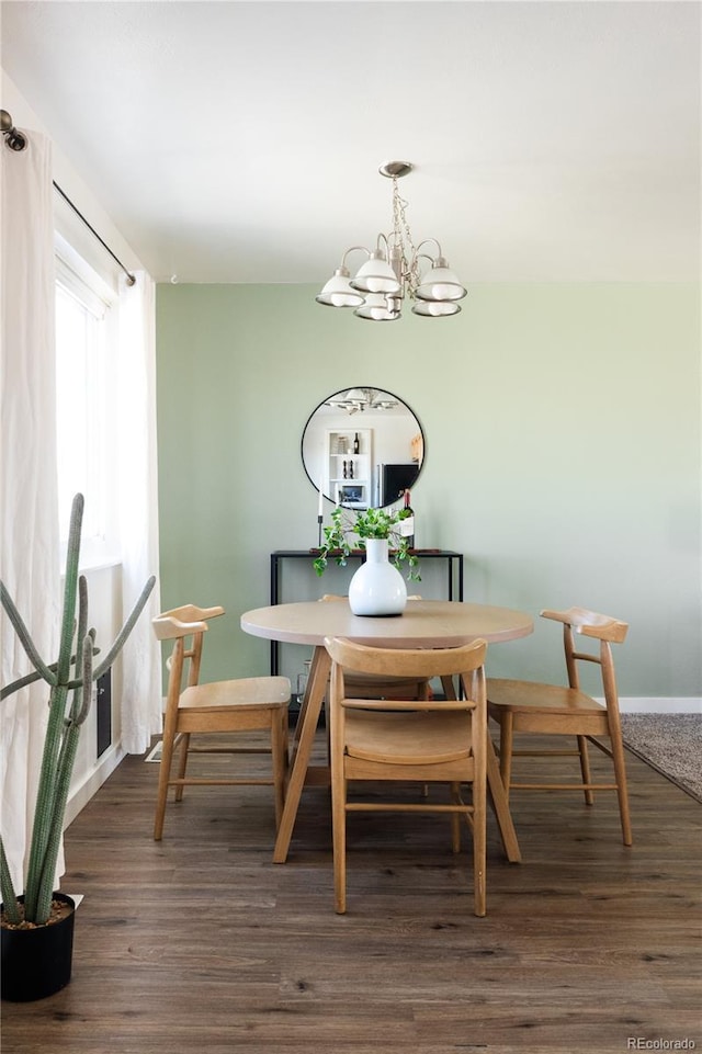 dining space with dark wood-type flooring and an inviting chandelier