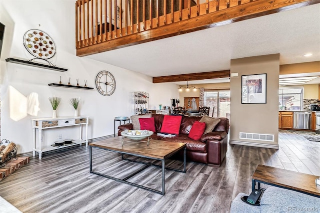 living room with dark hardwood / wood-style flooring, beam ceiling, and a textured ceiling