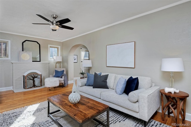 living room featuring crown molding, hardwood / wood-style floors, ceiling fan, and a fireplace