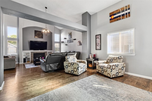 living room with a fireplace, a towering ceiling, dark hardwood / wood-style flooring, and a notable chandelier