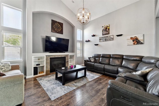 living room featuring built in shelves, a tile fireplace, high vaulted ceiling, dark hardwood / wood-style floors, and a chandelier