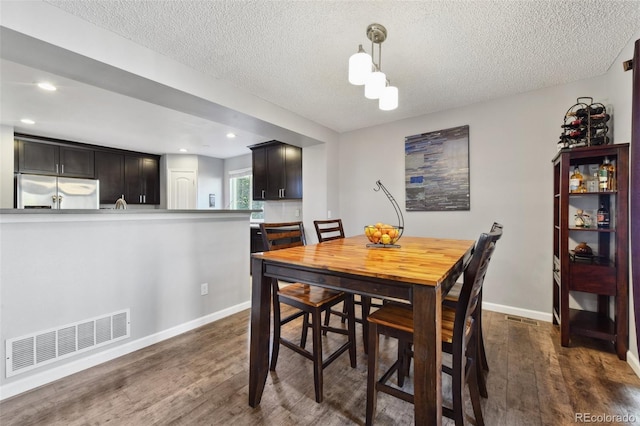 dining space with dark hardwood / wood-style floors and a textured ceiling