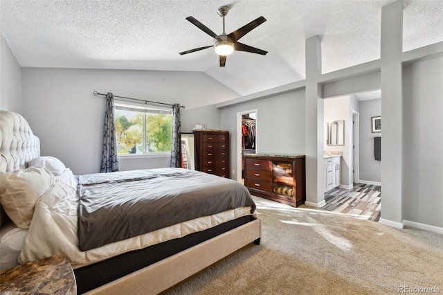 carpeted bedroom with ceiling fan, a spacious closet, connected bathroom, a closet, and lofted ceiling