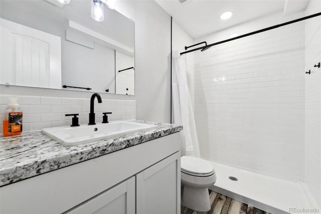 bathroom with vanity, backsplash, a shower with curtain, hardwood / wood-style flooring, and toilet