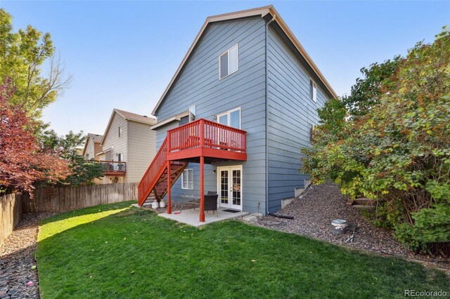 rear view of property featuring french doors, a patio, a deck, and a lawn