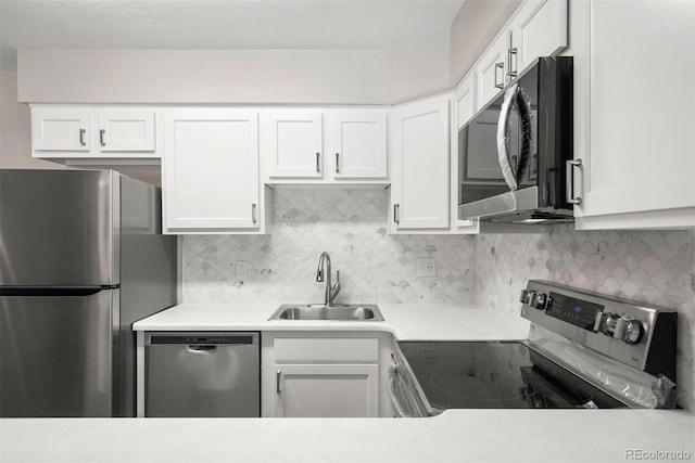 kitchen with tasteful backsplash, appliances with stainless steel finishes, sink, and white cabinets