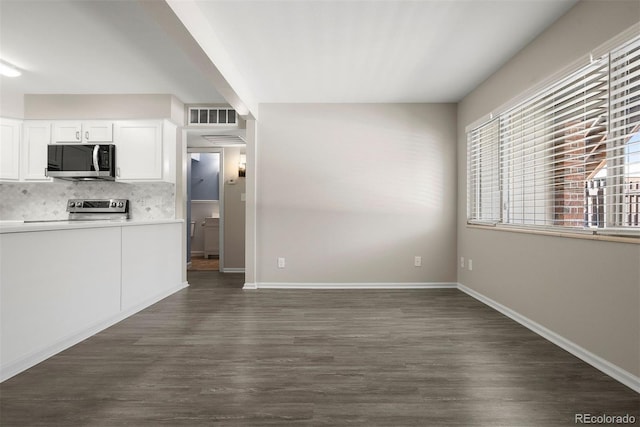 kitchen with tasteful backsplash, white cabinetry, stove, and dark hardwood / wood-style flooring