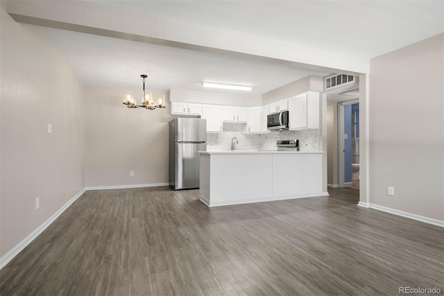 kitchen with appliances with stainless steel finishes, pendant lighting, white cabinets, decorative backsplash, and dark wood-type flooring