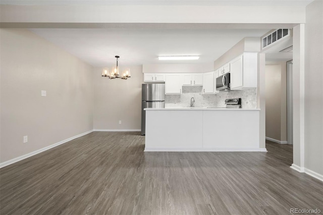 kitchen with white cabinetry, appliances with stainless steel finishes, backsplash, and dark hardwood / wood-style flooring