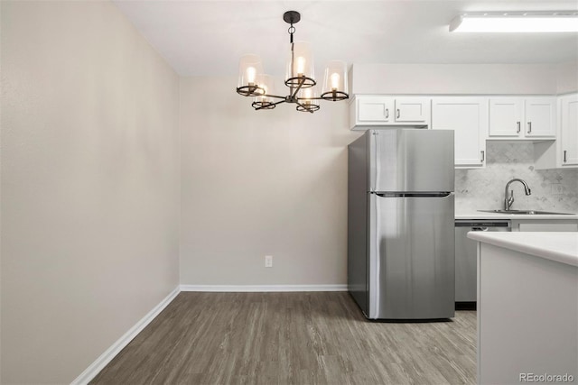 kitchen with pendant lighting, sink, stainless steel appliances, and white cabinets