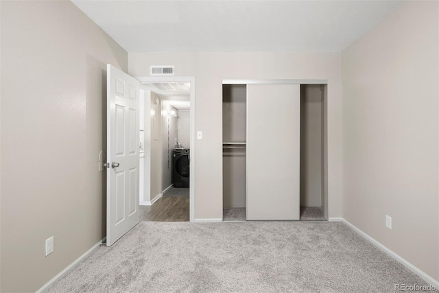 unfurnished bedroom with light carpet, washer / dryer, and a closet