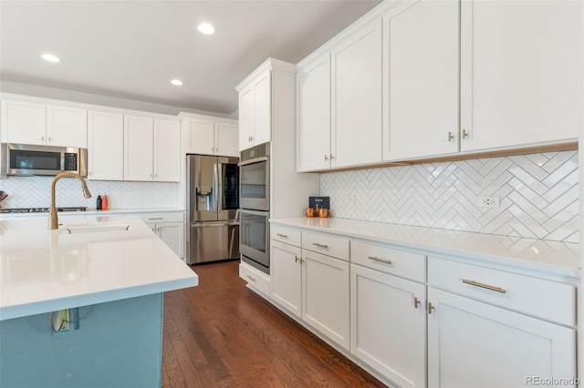 kitchen featuring dark hardwood / wood-style flooring, tasteful backsplash, stainless steel appliances, and white cabinetry