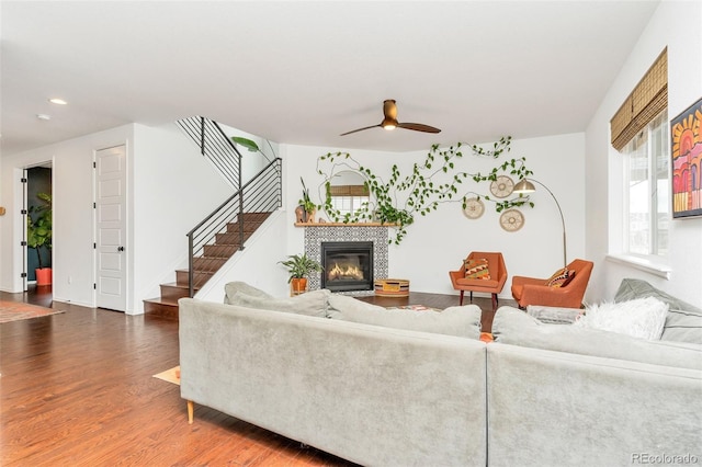 living room featuring ceiling fan, dark wood-type flooring, and a tiled fireplace