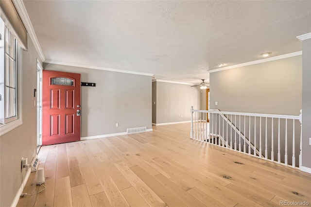 interior space with light wood-style floors, visible vents, crown molding, and ceiling fan