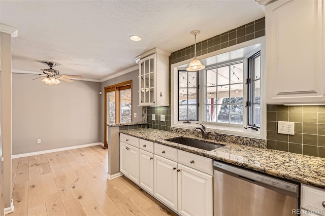 kitchen with ceiling fan, white cabinetry, dishwasher, a sink, and baseboards