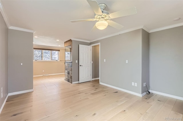 empty room featuring crown molding, light wood finished floors, baseboards, and a ceiling fan