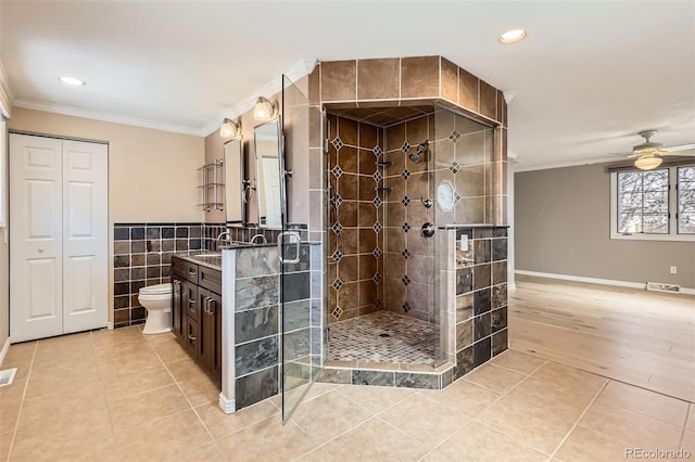 full bath with crown molding, tile patterned flooring, a stall shower, and tile walls