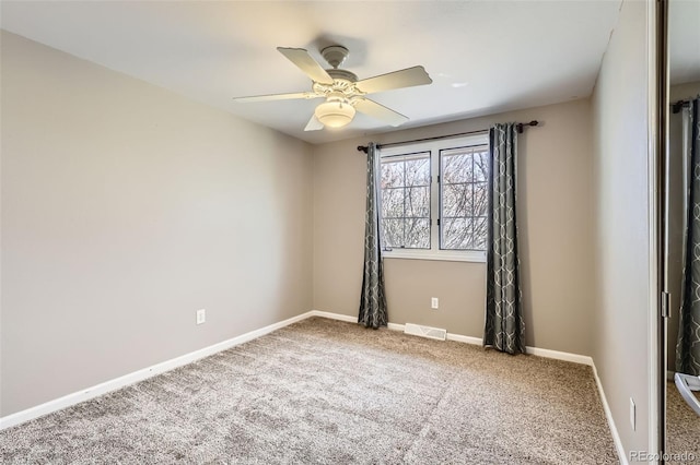 carpeted empty room featuring visible vents, ceiling fan, and baseboards