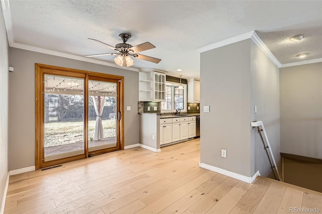 interior space with a textured ceiling, baseboards, a ceiling fan, and light wood-type flooring