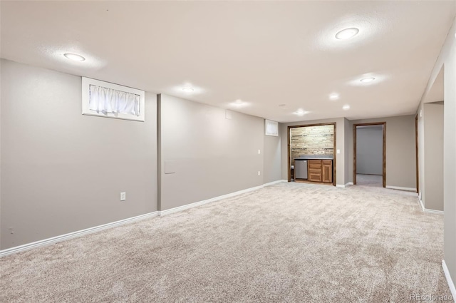 finished below grade area featuring baseboards, bar area, and light carpet