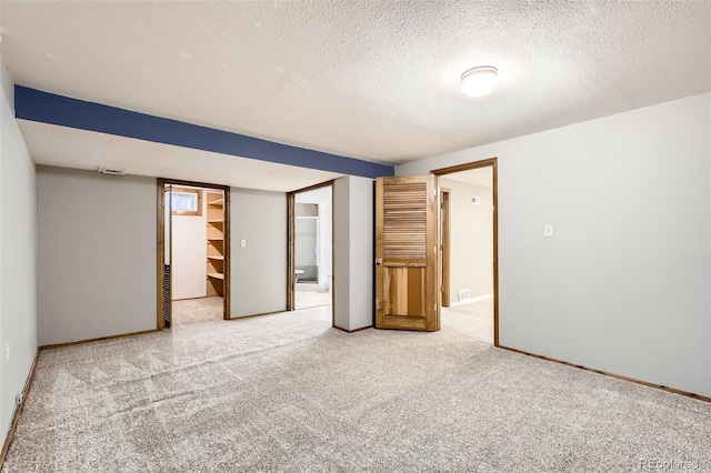 unfurnished room with baseboards, light carpet, and a textured ceiling