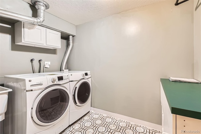 washroom featuring baseboards, a textured ceiling, cabinet space, washer and clothes dryer, and light floors