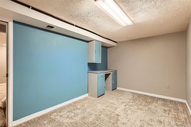 finished basement with a textured ceiling, light colored carpet, baseboards, and visible vents