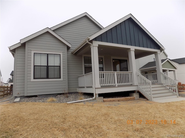 view of front of property with board and batten siding, a front yard, and covered porch