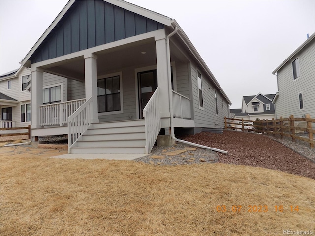 view of front of home featuring a porch, fence, board and batten siding, and a front lawn