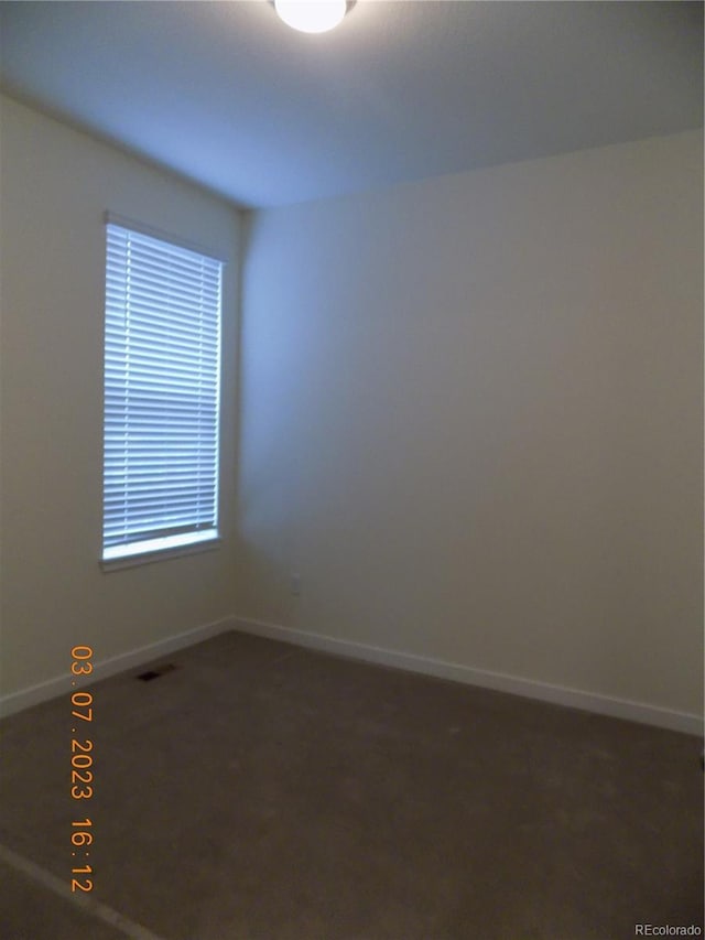 empty room with carpet, visible vents, and baseboards