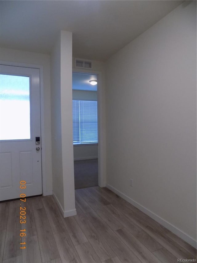 foyer entrance featuring visible vents, baseboards, and wood finished floors