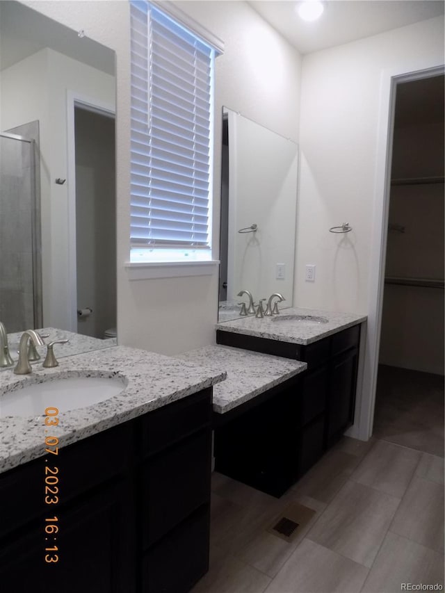 full bathroom featuring a stall shower, two vanities, and a sink