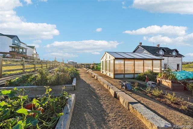 view of yard featuring an outdoor structure, a garden, fence, and an exterior structure