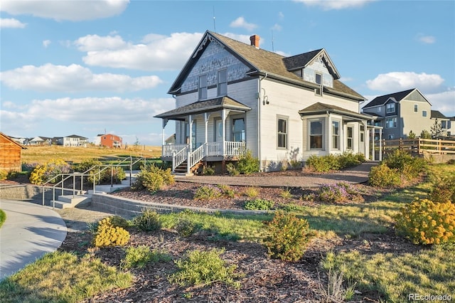 view of property exterior with a porch, fence, and a chimney