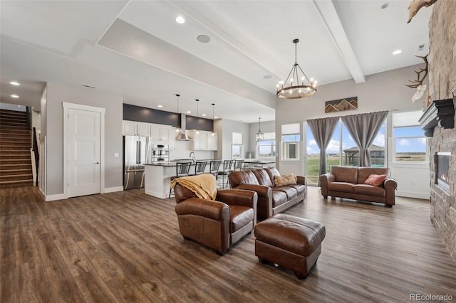 19751 Good Life Vw, Calhan, CO 80808 - living area featuring a chandelier, dark wood-style flooring, a stone fireplace, stairway, and beam ceiling