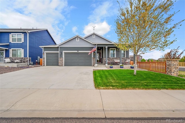 craftsman-style home featuring fence, a front lawn, stone siding, a garage, and driveway