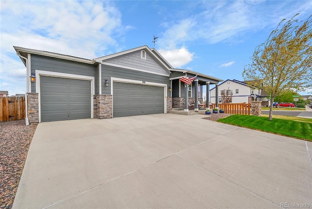 view of front of house with a garage, fence, stone siding, concrete driveway, and a porch