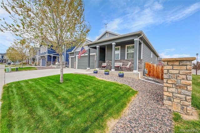view of front of house with a porch, a front yard, a garage, concrete driveway, and stone siding