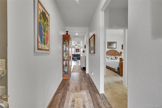 hallway featuring baseboards, visible vents, and wood finished floors