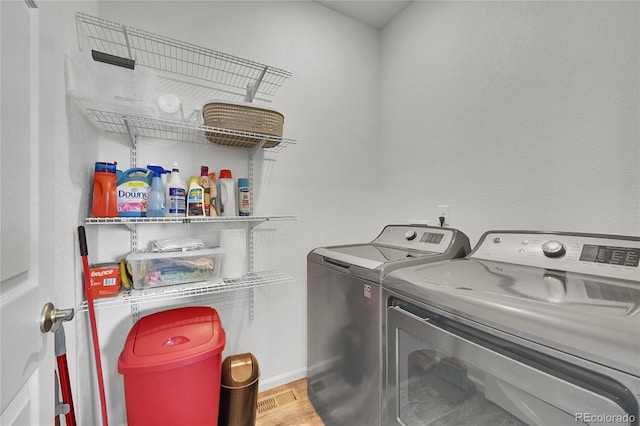 clothes washing area featuring baseboards, laundry area, washer and clothes dryer, and wood finished floors